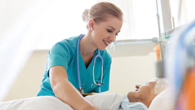 Nurse tucking an elderly patient into bed