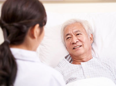 A nurse talking to a very comfortable patient in a hospital bed