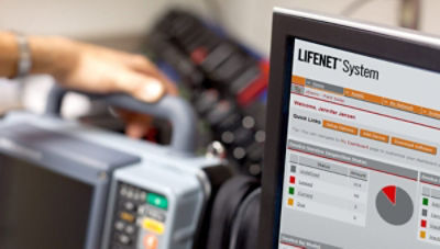 Sistem LIFENET afișat pe un ecran de calculator, lângă un monitor-defibrilator LIFEPAK 15