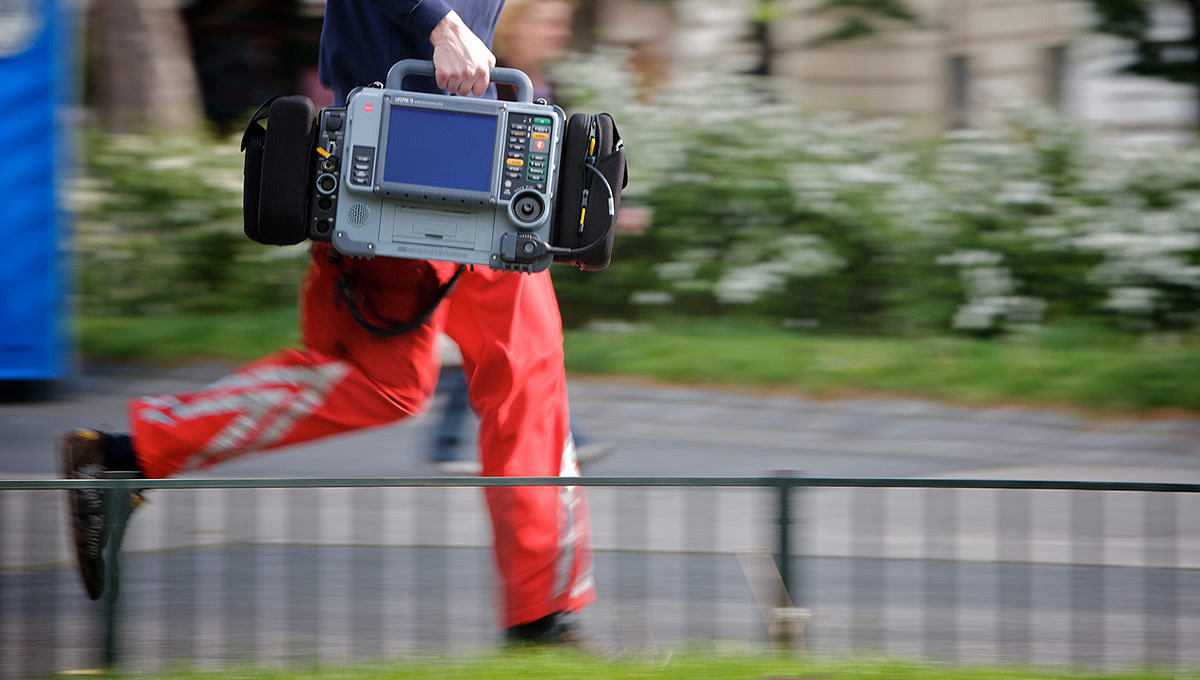 Paramedic running to a patient with a LIFEPAK 15 monitor/defibrillator in his right hand.