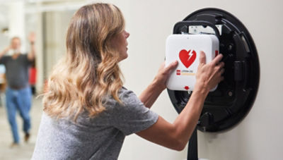 A bystander retrieves a LIFEPAK CR2 defibrillator (also known as an automatic external defibrillator) from a wall storage unit