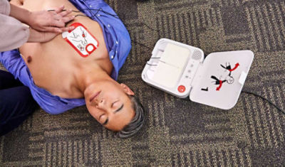Mężczyzna leżący na ziemi z defibrylatorem AED LIFEPAK CR2 podłączonym do klatki piersiowej