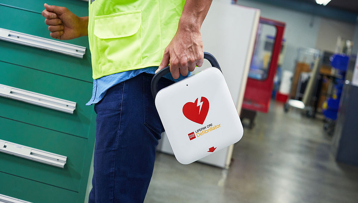 A bystander is running through a factory floor with the LIFEPAK CR2 defibrillator