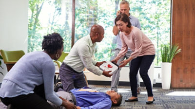 Bystanders holding the LIFEPAK CR2 defibrillator and assisting man lying on ground