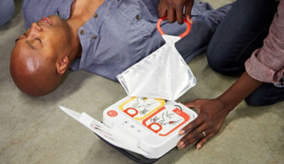 A bystander unpacks an AED next to an sudden cardiac arrest victim