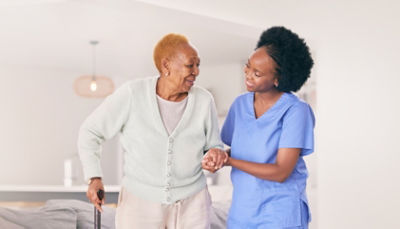 Nurse helping elderly patient with cane