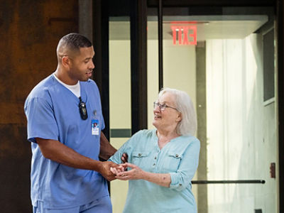 Male nurse wearing a Vocera Smartbadge providing care to a senior living patient 