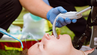 EMT uses teh McGRATH MAC video laryngoscope on a young patient in a public setting 