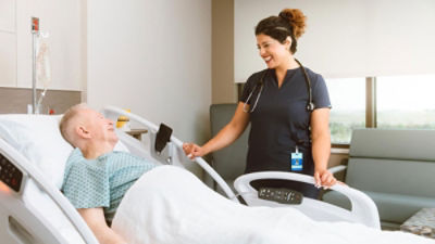 nurse smiling at patient in bed