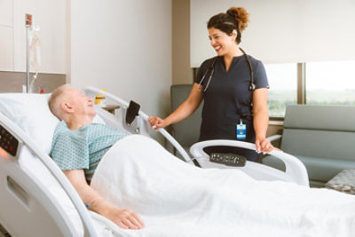 Nurse caring for patient laying in a Procuity hospital bed 