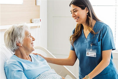 Nurse standing beside patient in hospital bed