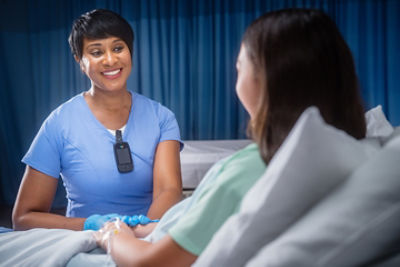 A nurse comforts a patient in the hospital while a wearing a Vocera SmartBadge - hands-free communication 