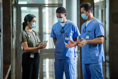 Doctors and nurses walking in a hospital wearing Vocera Badges - hands-free communication devices