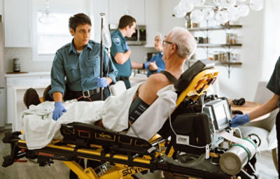 Técnico en emergencias con un paciente en una camilla Power Pro XT de Stryker y usando el monitor LIFEPAK 15