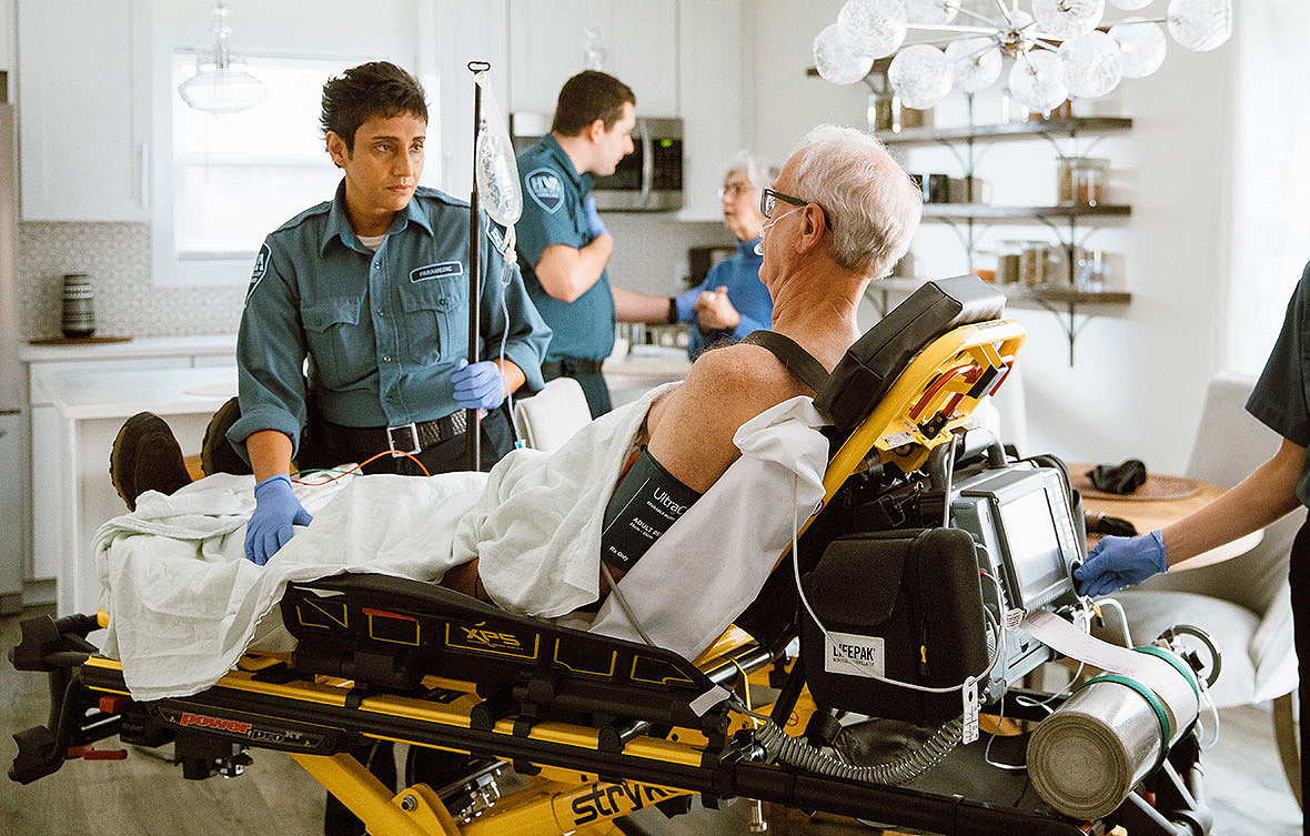Técnico en emergencias con un paciente en una camilla Power Pro XT de Stryker y usando el monitor LIFEPAK 15