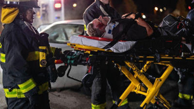 Firefighter EMS pulling a patient on a Power-PRO 2 from a night time car crash
