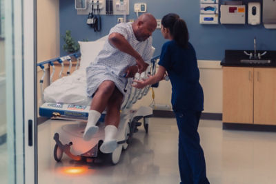 Nurse assisting patient from a electric hospital stretcher 