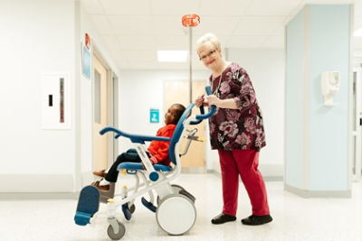 A nurse pushes a pediatric patient in the Prime TC patient transport chair 