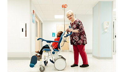 A nurse pushes a pediatric patient in the Prime TC patient transport chair 