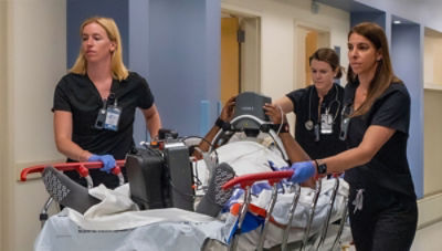 Three nurses wheeling patient down hospital corridor on Prime-X stretcher being treated with LIFEPAK-35 and LUCAS-3