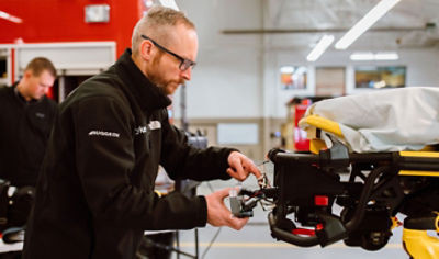 ProCare technician fixing powered ambulance cot