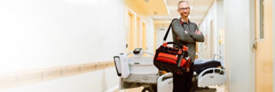 technician in hallway with arms crossed and duffle bag over shoulder