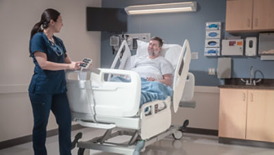 nurse using ProCeed foot board controller while patient lying in bed