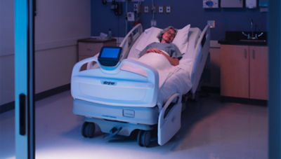 Patient in dark room laying in ProCuity hospital bed