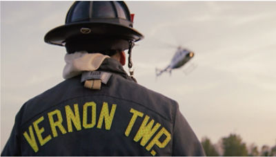Firefighter from Vernon Township looking into the sky at a rescue helicopter making a descent