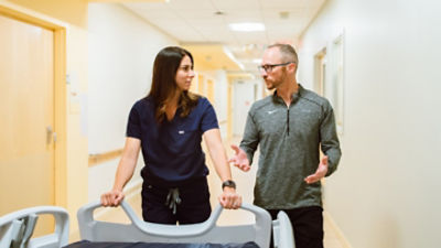 Nurse and Stryker sales rep walking down an aisle with a ProCuity bed