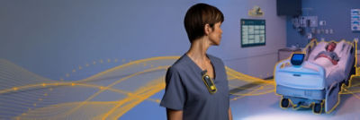 Nurse wearing Sync Badge looking back at patient in ProCuity bed