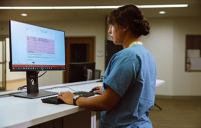 Enfermeira no hospital a rever os dados administrados do EMS através do Sistema LIFENET da Stryker num computador de secretária