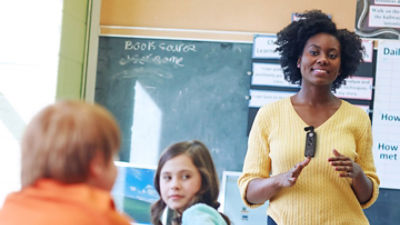 teacher wearing Sync Badge talking with two young students