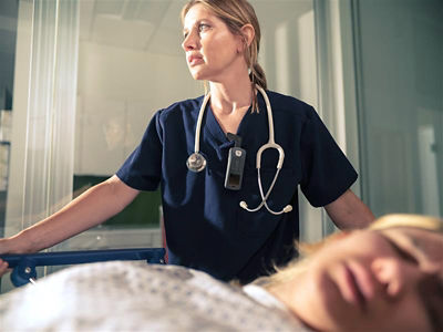 Clinician wearing Sync Badge standing next to patient in hospital bed