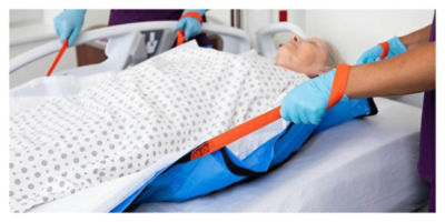 Two nurses sliding a patient on a ProCuity bed