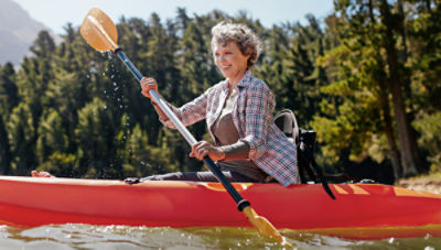 Woman canoeing on lake after restored mobility and relief through vertebroplasty treatment