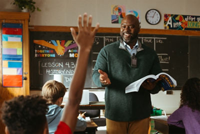 School teacher interacting with students at the front of a classroom