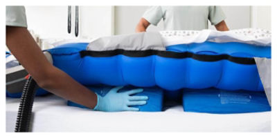 Two nurses turning a patient using a stabilizing wedge to prevent pressure injuries