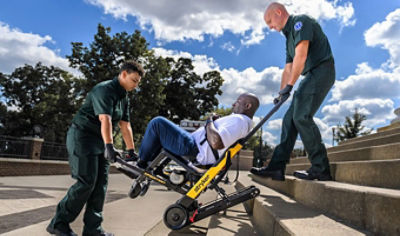 Paramedics transport adult patient down stairs using Xpedition powered stair chair  